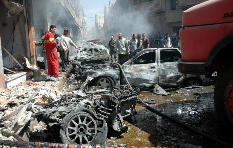 Emergency personnel and civilians inspect the site following a car bomb explosion in the Abbasiyah neighborhood of Syria's central city of Homs on April 29, 2014. (Photo: AFP / STR)