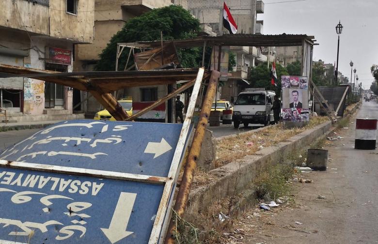 Syrian government forces stand at a checkpoint, decorated with pictures of President Bashar al-Assad and Syrian flags, leading to the Jab al-Jandali district of the central city of Homs on May 7, 2014, after Syrian government forces regained control of the city. (Photo: AFP/STR)