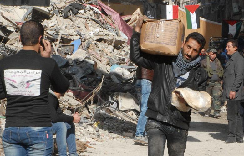 A handout picture released by the official Syrian Arab News Agency (SANA) on January 30, 2014 shows residents of Syria's besieged Yarmuk Palestinian refugee camp, south of Damascus, receiving food parcels from the UN Palestinian refugee agency (UNRWA). (Photo: AFP/SANA)